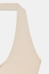 Top de punto con cuello halter y escote redondo profundo, sin mangas y corte ajustado.