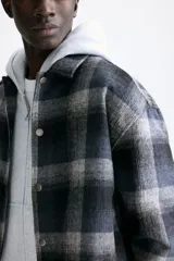 Sobrecamisa de corte relajado en tejido suave con diseño a cuadros. Presenta cuello inglés, cierre frontal con botones a presión, hombros caídos y mangas largas con puños abotonados.