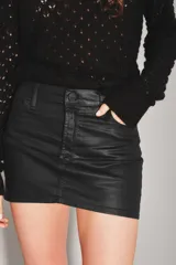 Minifalda negra de tiro medio, confeccionada en material con acabado engomado o efecto cuero, con diseño de cinco bolsillos y cierre frontal con botón y cremallera.