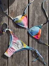 Bikini de dos piezas con estampado abstracto multicolor. El top es de triángulos movibles con almohadillas desmontables y se ata al cuello y la espalda. La bombacha es vedetina con tiritas ajustables a los costados.