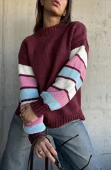 Sweater de tejido de punto con cuello redondo, cuerpo en color bordeaux y mangas con diseño de rayas horizontales en tonos bordeaux, blanco, rosado y celeste.