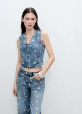 Chaleco denim con bordado de margaritas, corte crop, cuello en V y cierre frontal con botones.