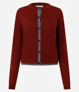 Cardigan de punto Marfinno, color negro con detalles en blanco en la botonera y el ruedo. Presenta cuello redondo, mangas largas y cierre frontal con botones oscuros.