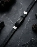 Pulsera masculina con banda central de cuerina negra grabada con diseño de guarda griega y detalles laterales en acero inoxidable.