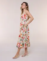 Vestido midi evasé de lino estampado con diseño floral multicolor sobre base beige. Cuenta con escote cuadrado, tirantes anchos y cierre invisible en la espalda.
