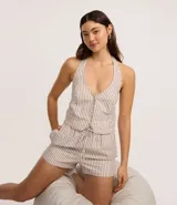 Blusa de jeans con cuello halter y escote en V, diseño a rayas verticales en color beige y blanco. Presenta cierre frontal con botones forrados y lazo para atar al cuello.