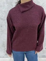 Polera de punto color bordó, con cuello alto abierto lateralmente, mangas largas amplias y corte recto.