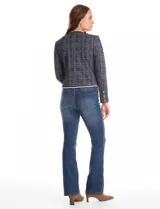 Chaqueta de tejido tweed en tono azul con sutiles destellos de lúrex. Presenta cuello a la base, abertura frontal y bolsillos decorativos. Las mangas largas incluyen detalle de botones metálicos dorados en los puños, y cuenta con vivos a contratono en los bordes.