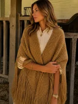 Ruana de lana merino color camel, con diseño triangular, tejido artesanal texturizado y terminación con maxi flecos largos en todo el borde.