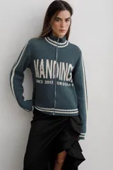 Campera tejida de algodón en color rojo, con cierre frontal completo, cuello alto y puños acanalados con detalles de rayas blancas. Presenta un diseño gráfico con texto blanco en el frente.