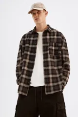 Camisa de manga larga con cuello inglés, tapeta clásica y canesú en la espalda. Presenta un bolsillo superior abierto y puños abotonados. El bajo es redondeado.