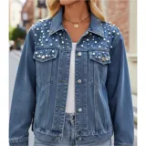 Campera de jean color negro con apliques de perlas en la parte superior frontal. Presenta cuello clásico, cierre frontal con botones metálicos y dos bolsillos en el pecho.