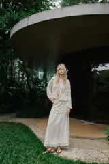 Blusa de escote en pico y manga larga con puños elásticos. Presenta un diseño semitransparente con bordados florales a tono, cintura elástica y cierre frontal mediante lazos con abalorios decorativos.