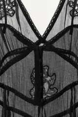 Top semitransparente negro de gasa con escote en pico, tirantes finos y detalles de bordados florales a tono. Presenta godets y acabados en puntilla, con cierre de botones forrados en la espalda.