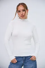 Polera blanca de manga larga, con cuello alto y bordes ondulados en el cuello y el dobladillo.