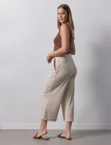 Pantalón capri plisado color beige, marca Dictionary, con pretina ancha elastizada y bolsillos delanteros.
