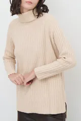 Polera de tejido de punto acanalado en color beige, con cuello alto, manga larga y diseño de corte recto con aberturas laterales en el ruedo.