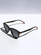 Lentes de sol Osten modelo Maui, con armazón negro de diseño redondeado y detalles en color naranja en las patillas. Cuentan con cristales polarizados con protección UV 400.