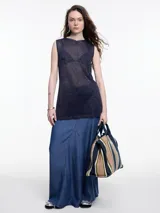 Musculosa sin mangas de tejido translúcido con sutil brillo metálico. Presenta un calce relajado, largo por debajo de la cadera y aberturas laterales.