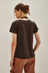 Remera de algodón color marrón oscuro con estampa frontal de estilo místico que incluye manos en posición de mudra, una flor de loto y la frase 'Feel it in your soul'.