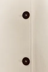Abrigo corto de corte recto confeccionado en mezcla de lana, con cuello solapa, cierre frontal con botones oscuros, bolsillos delanteros y mangas largas con trabilla ajustable.