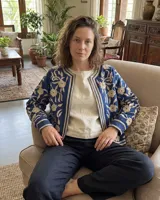 Chaqueta azul índigo de algodón con bordados florales en color crudo, de corte recto y sin cuello.