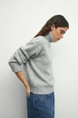 Polera de cuello alto en color gris, con diseño de textura tramada y puños y ruedo acanalados.