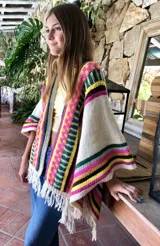 Chal tejido a mano en lana merino, con diseño de jacquard geométrico multicolor a rayas en tonos crudo, fucsia, verde, amarillo y marrón, terminado con flecos en los extremos.