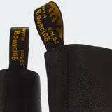 Botas Dr. Martens 1460 de cuero negro, con cordones, suela con cámara de aire y costuras amarillas visibles en la vira.