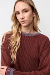 Pullover de punto acanalado en color marrón, con corte oversize, cuello redondo y detalles en contraste en el cuello y los puños.