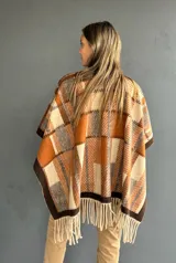 Ruana abierta con diseño de cuadros en tonos tierra, naranja y beige, con terminación de flecos en el ruedo.