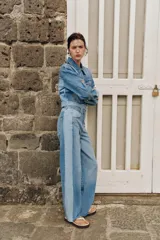 Jeans de tiro medio con diseño barrel y paneles laterales en un tono de denim más claro que contrasta con el centro. Presenta cinco bolsillos, cierre frontal con cremallera y botón, y bajo con acabado sin costura.