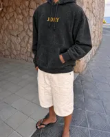 Canguro con capucha de algodón y poliéster, color negro con efecto acid wash, corte regular fit y estampa en la espalda con diseño en blanco y negro de una persona con un gato dentro de un sello postal, acompañada de texto en celeste.
