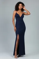 Vestido largo de fiesta color azul marino con acabado brillante, escote en V profundo, tirantes finos y espalda descubierta. Presenta un corte ajustado al cuerpo con una abertura lateral en la falda.