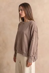 Sweater de algodón peinado con efecto lavado, de corte oversize, cuello redondo y mangas largas con costuras visibles.