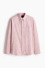 Camisa de sarga de algodón de corte relajado, con estampado a cuadros en tonos rosados y blancos, cuello americano, manga larga con puños abotonados y un bolsillo frontal en el pecho.