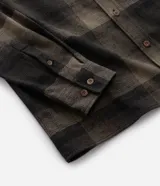 Camisa de franela a cuadros en tonos de azul marino y gris oscuro, con corte regular, manga larga, cuello camisero, cierre frontal de botones y un bolsillo en el pecho.