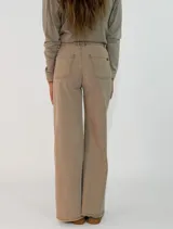 Pantalon de corte recto y tiro medio, confeccionado en gabardina color marrón. Presenta cierre frontal con botón y bolsillos laterales.