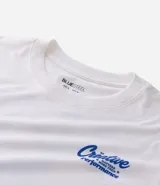 Remera de algodón color blanco tiza, manga corta y cuello redondo. Presenta un estampado grande en la espalda con la palabra "Creative" en tipografía cursiva iridiscente, un oso de goma con efecto holográfico en tonos azules y rosados, y el texto "MATTERS MORE THAN P¡FORMACE" debajo.