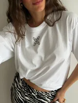 Remerón blanco de algodón con cuello redondo, mangas cortas y un pequeño estampado en el centro del pecho.