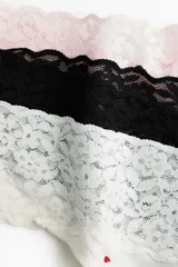 Pack de tres bombachas tipo colaless de tiro bajo con cintura en V y ribete ancho de encaje. El set incluye una prenda rosa, una negra y una blanca con estampado de corazones rojos.