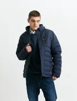 Campera acolchada de color gris, con capucha desmontable, cierre frontal y bolsillos laterales con cremallera. Presenta un diseño de costuras horizontales y detalles en color naranja en los tiradores de los cierres.