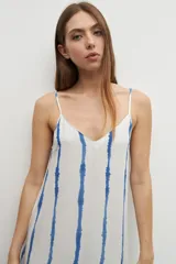 Maxi vestido blanco con rayas verticales azules y estampado de paisaje en el ruedo.