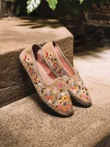 Bailarina de cuero serraje color beige, con detalle de flores bordadas en el lateral y suela plana con costura lateral visible.