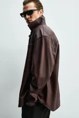 Sobrecamisa relaxed fit de cuero color marrón oscuro, con cuello solapa, manga larga con puño abotonado, bolsillo de parche en el pecho y cierre frontal de botonadura.