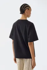 Remera negra de corte oversized con diseño estampado de Pink Floyd en el frente, cuello redondo y mangas cortas.