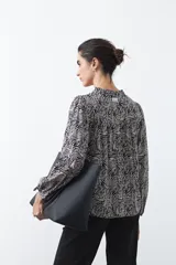 Camisa de manga larga color marrón con estampado de lunares blancos, cuello mao y cierre frontal con botones.