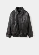 Chaqueta oversize de piel de ovino marrón oscuro, con cuello camisero, cierre frontal de cremallera y botones a presión ocultos bajo tapeta, bolsillos frontales de ribete y bajo elástico fruncido.