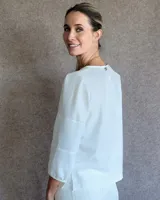 Blusa de mangas tres cuartos con diseño de corte recto y cuello redondo. Presenta costuras horizontales decorativas en las mangas y un acabado liso.