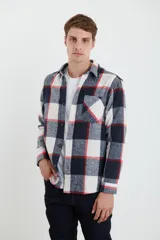 Sobrecamisa de tejido suave con diseño de cuadros en tonos azul marino, blanco y líneas rojas. Presenta cuello clásico, cierre frontal con botones, un bolsillo superior en el pecho y mangas largas con puños abotonados.